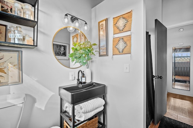 bathroom featuring a sink, toilet, and wood finished floors