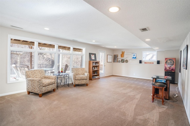 living area with carpet flooring, baseboards, visible vents, and a textured ceiling