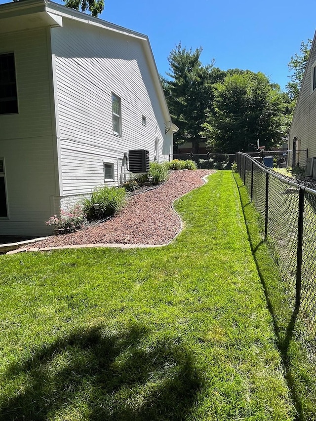 view of side of home featuring central air condition unit, a lawn, and fence