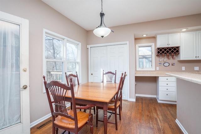 dining area with dark wood finished floors, visible vents, and a wealth of natural light