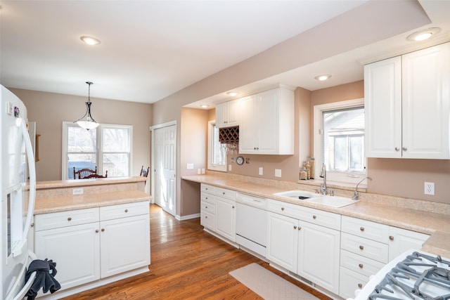 kitchen with white cabinetry, white appliances, wood finished floors, and a sink