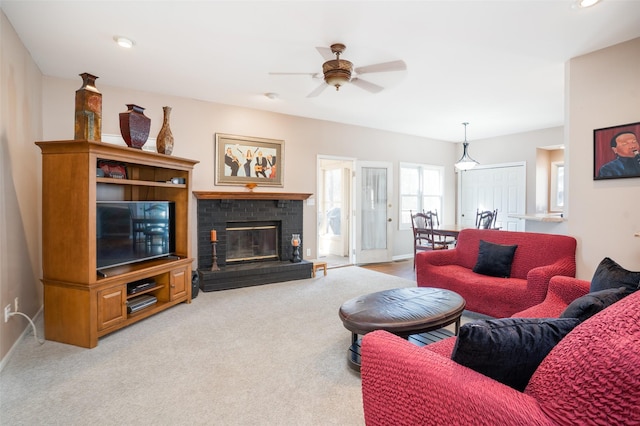 living area featuring a brick fireplace, carpet flooring, a ceiling fan, and baseboards