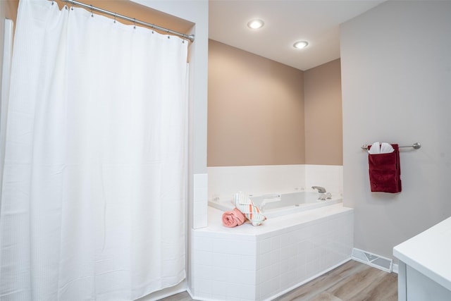 bathroom featuring a bath, visible vents, baseboards, and wood finished floors