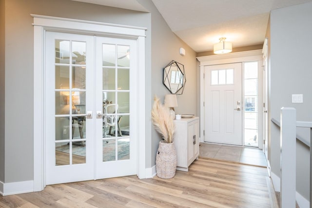 foyer with light wood-type flooring, french doors, and baseboards