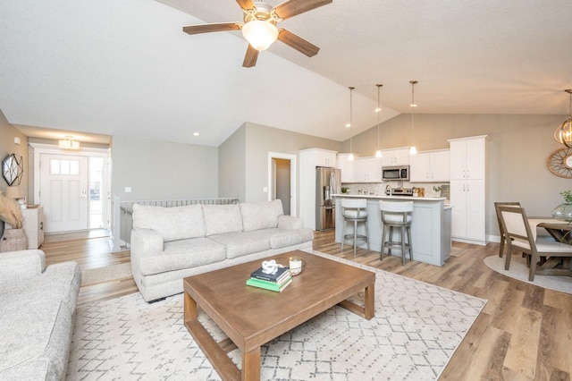 living area with a ceiling fan, light wood-type flooring, and lofted ceiling