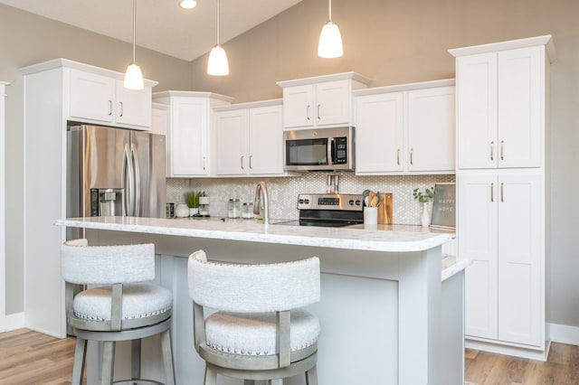 kitchen featuring decorative backsplash, white cabinets, light wood-style flooring, and stainless steel appliances