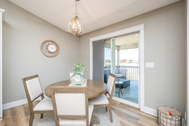 dining room featuring a notable chandelier, baseboards, and light wood-type flooring