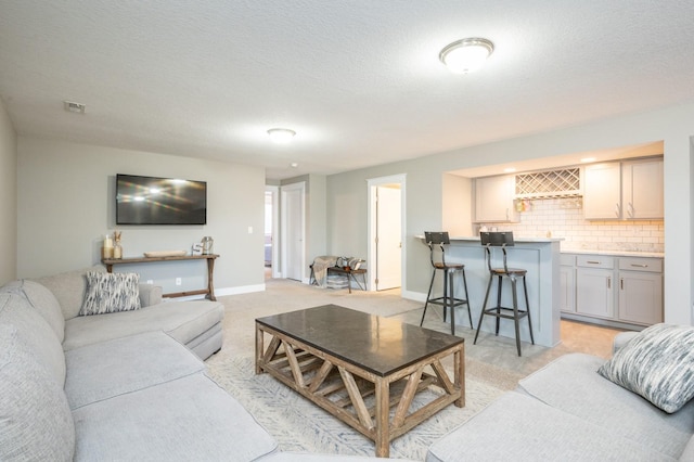 living area featuring bar area, visible vents, baseboards, and a textured ceiling