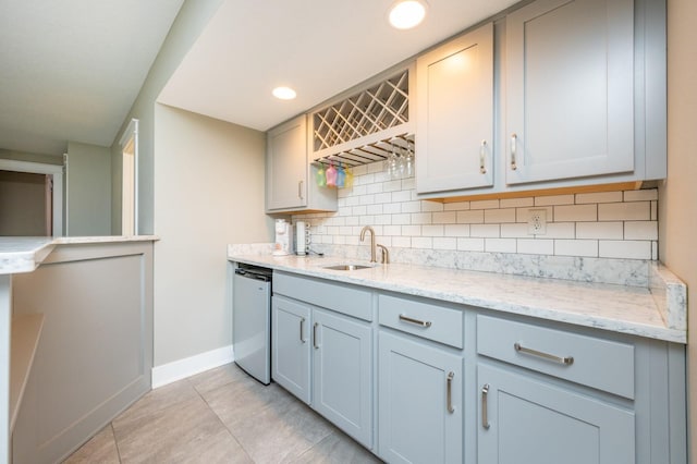 kitchen with a sink, backsplash, light tile patterned flooring, baseboards, and dishwasher