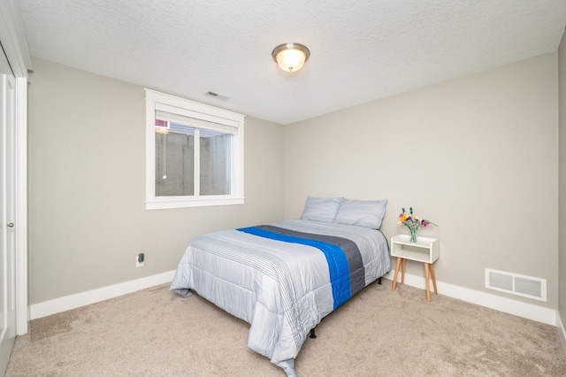 carpeted bedroom featuring visible vents, baseboards, and a textured ceiling