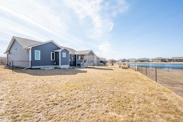 rear view of house featuring a residential view, a lawn, a fenced backyard, and a water view