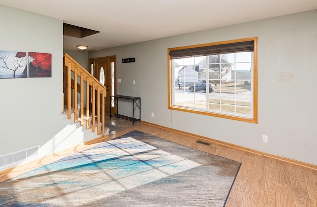 interior space with stairs, wood finished floors, visible vents, and baseboards