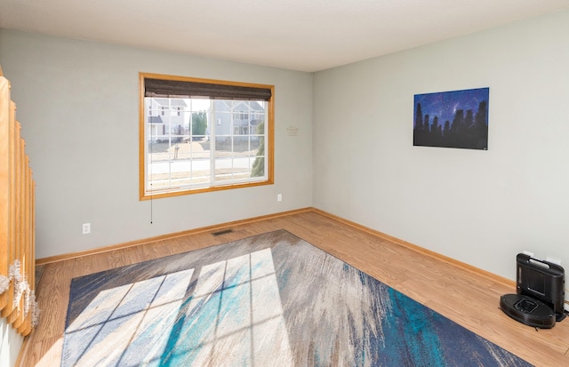 spare room featuring visible vents, baseboards, and wood finished floors