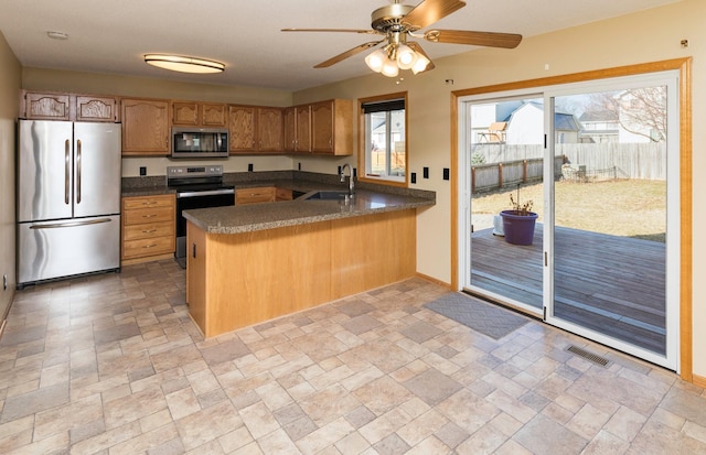 kitchen featuring visible vents, a peninsula, a sink, appliances with stainless steel finishes, and stone finish flooring