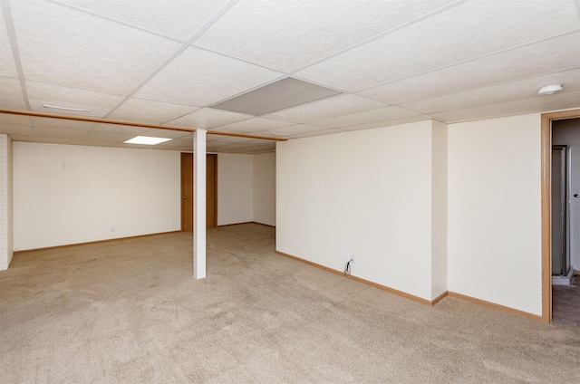 finished below grade area featuring carpet, baseboards, and a drop ceiling