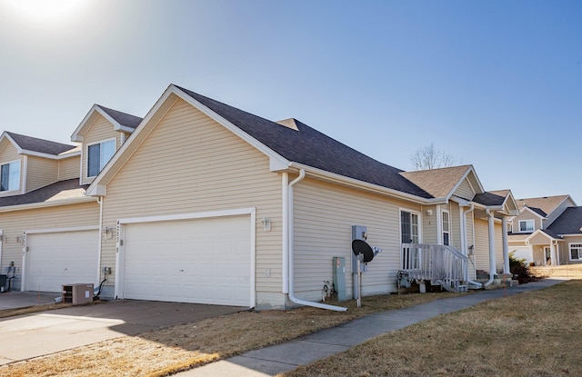 view of side of home with central air condition unit, concrete driveway, and a garage