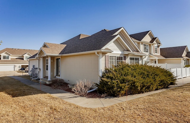 view of property exterior featuring roof with shingles, an attached garage, and fence