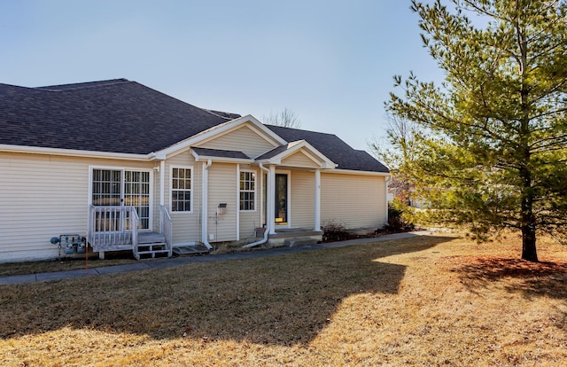 view of front of house with roof with shingles and a front yard