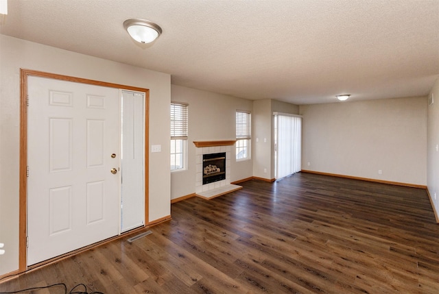 foyer with baseboards, visible vents, a fireplace, dark wood-style flooring, and a textured ceiling