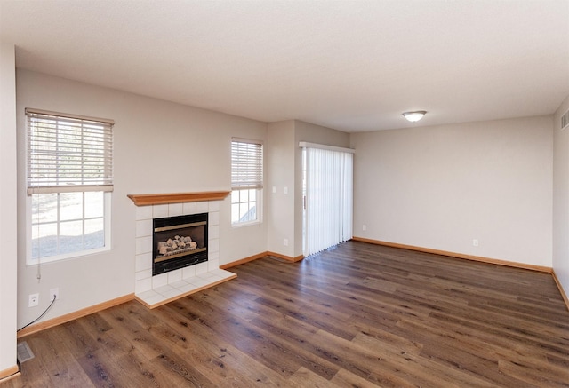 unfurnished living room with visible vents, wood finished floors, a tile fireplace, and a healthy amount of sunlight