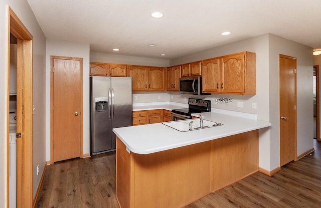 kitchen with recessed lighting, appliances with stainless steel finishes, a peninsula, and dark wood-style flooring