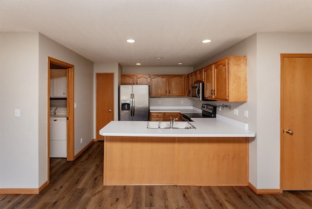 kitchen featuring a sink, wood finished floors, stainless steel appliances, a peninsula, and light countertops