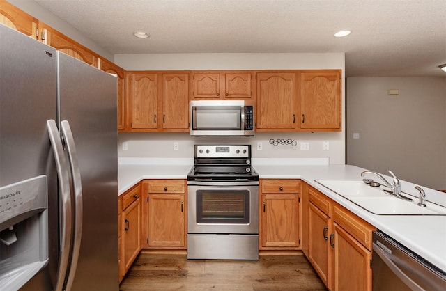 kitchen with light wood-style flooring, a sink, recessed lighting, stainless steel appliances, and light countertops