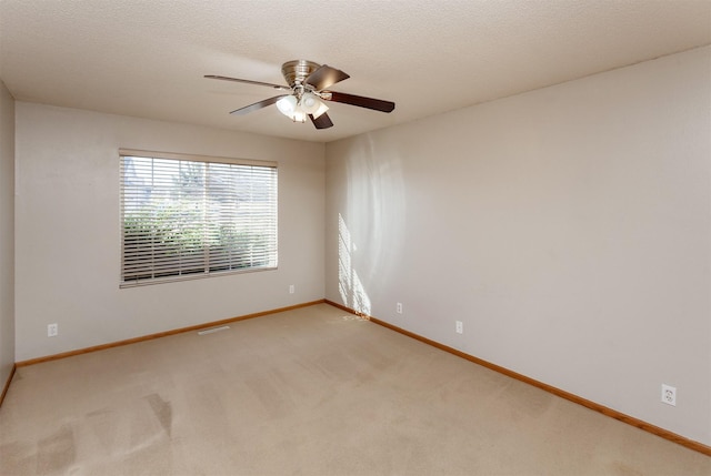 spare room featuring visible vents, ceiling fan, baseboards, carpet floors, and a textured ceiling