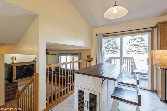 dining room featuring lofted ceiling, marble finish floor, a ceiling fan, and a tile fireplace