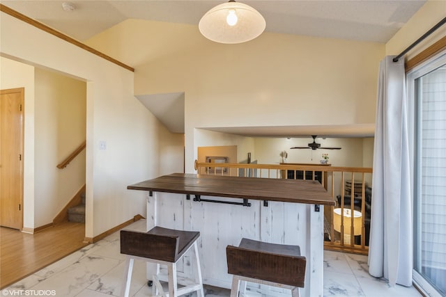 bar featuring lofted ceiling, marble finish floor, a ceiling fan, baseboards, and stairs