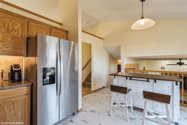 kitchen with a ceiling fan, brown cabinets, vaulted ceiling, stainless steel refrigerator with ice dispenser, and marble finish floor