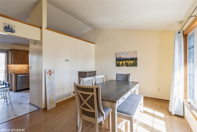 dining room with visible vents, light wood-style flooring, baseboards, and lofted ceiling