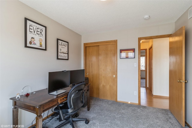 office area with a textured ceiling, carpet, visible vents, and baseboards