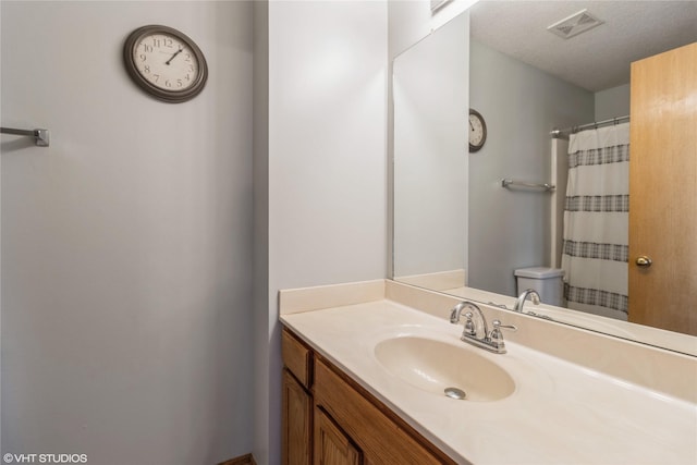 bathroom featuring vanity, toilet, visible vents, and a textured ceiling