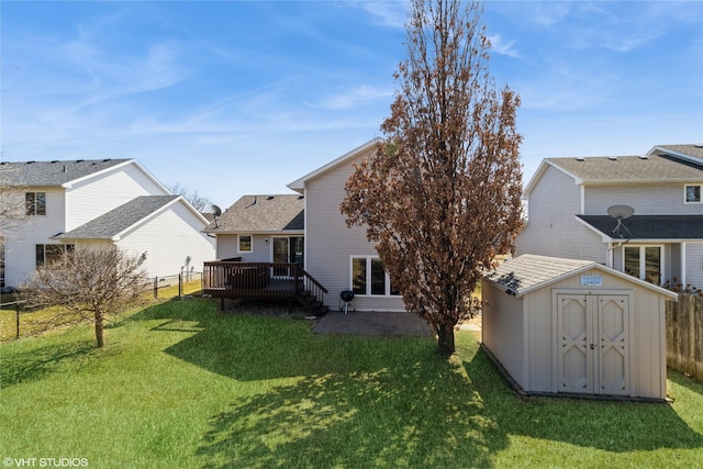 back of house featuring a lawn, a deck, fence, a storage shed, and an outdoor structure