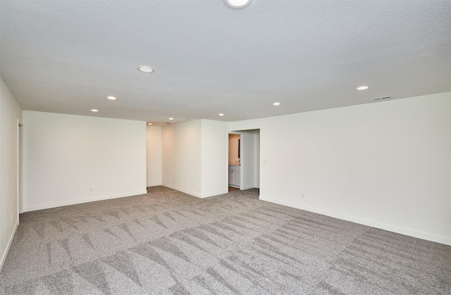 unfurnished room with visible vents, baseboards, carpet floors, recessed lighting, and a textured ceiling