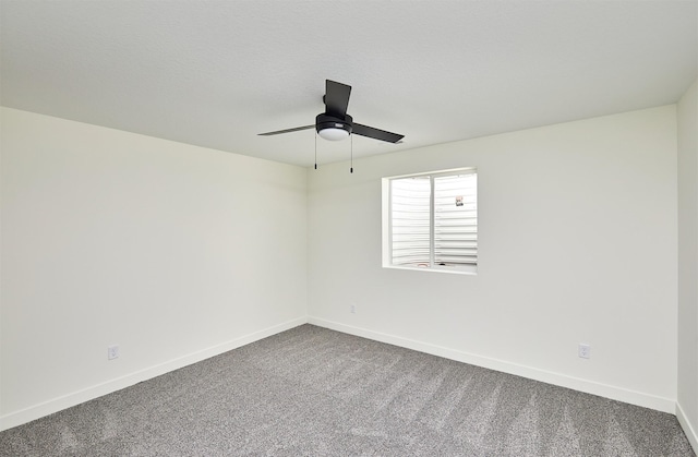 empty room featuring baseboards, ceiling fan, and dark colored carpet