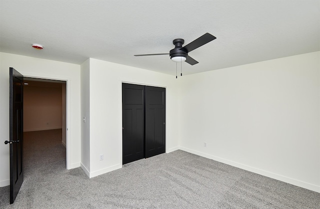 unfurnished bedroom featuring a textured ceiling, a closet, carpet flooring, baseboards, and ceiling fan