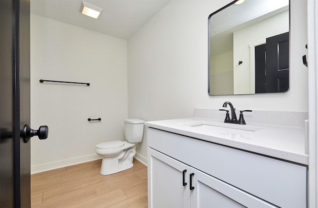 bathroom with baseboards, toilet, wood finished floors, and vanity