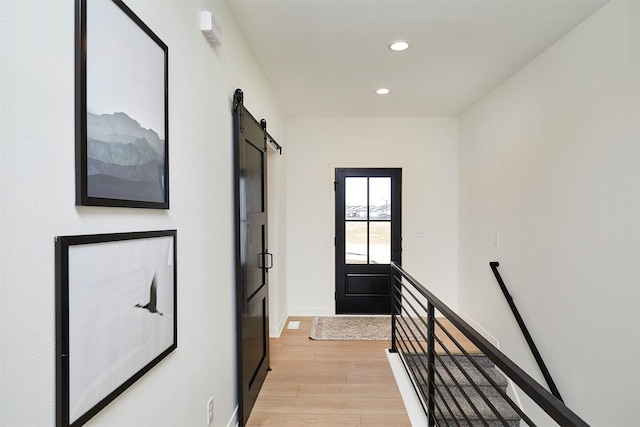 hallway featuring an upstairs landing, recessed lighting, a barn door, light wood-style floors, and baseboards