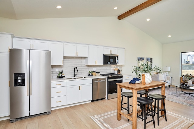 kitchen featuring a sink, stainless steel appliances, light countertops, light wood-type flooring, and backsplash