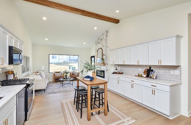 kitchen featuring range with gas stovetop, beam ceiling, decorative backsplash, light wood-style floors, and open floor plan