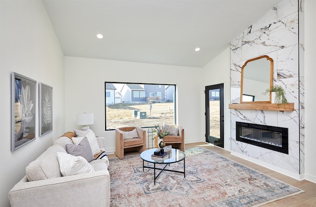 living room with recessed lighting, wood finished floors, a high end fireplace, and vaulted ceiling