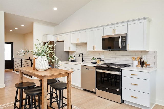 kitchen with light countertops, light wood finished floors, appliances with stainless steel finishes, and a sink