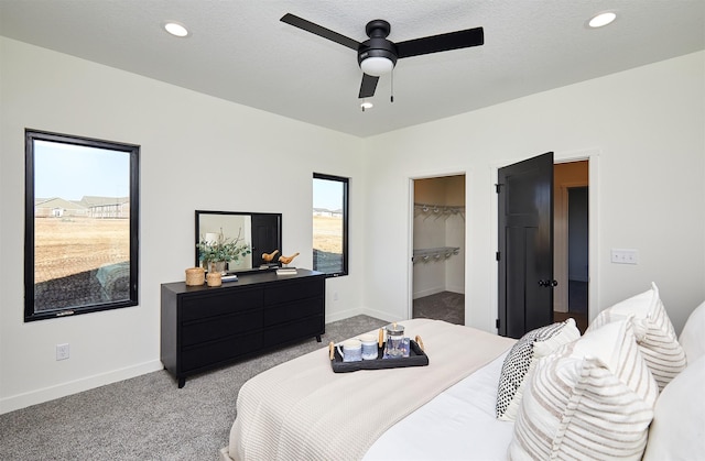 bedroom featuring light carpet, recessed lighting, a spacious closet, and baseboards