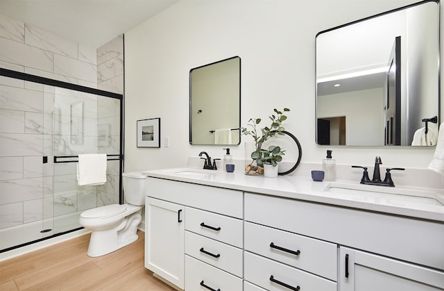 bathroom with wood finished floors, a stall shower, toilet, and a sink