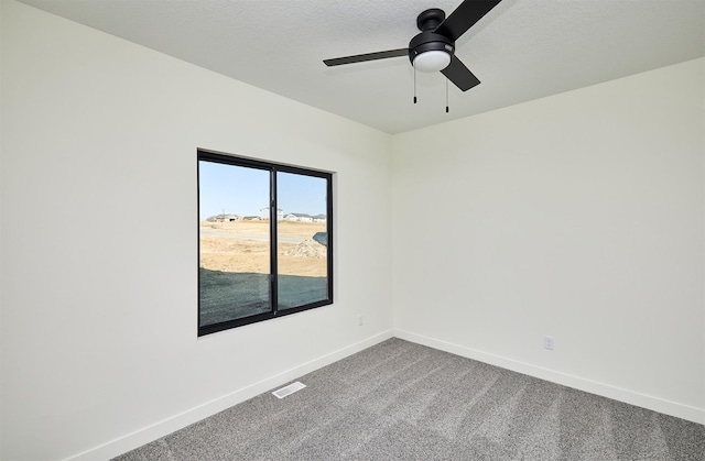 empty room featuring a ceiling fan, visible vents, baseboards, carpet floors, and a textured ceiling