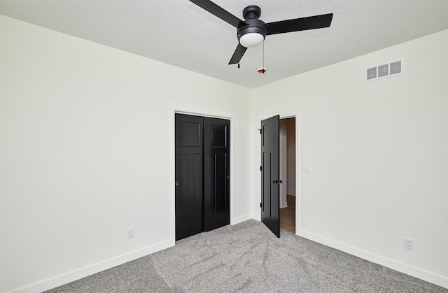 unfurnished bedroom featuring visible vents, light carpet, a textured ceiling, and baseboards