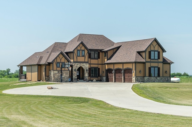 english style home with stucco siding, stone siding, curved driveway, and a front yard