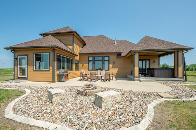 rear view of house featuring a patio, an outdoor fire pit, a shingled roof, and a hot tub